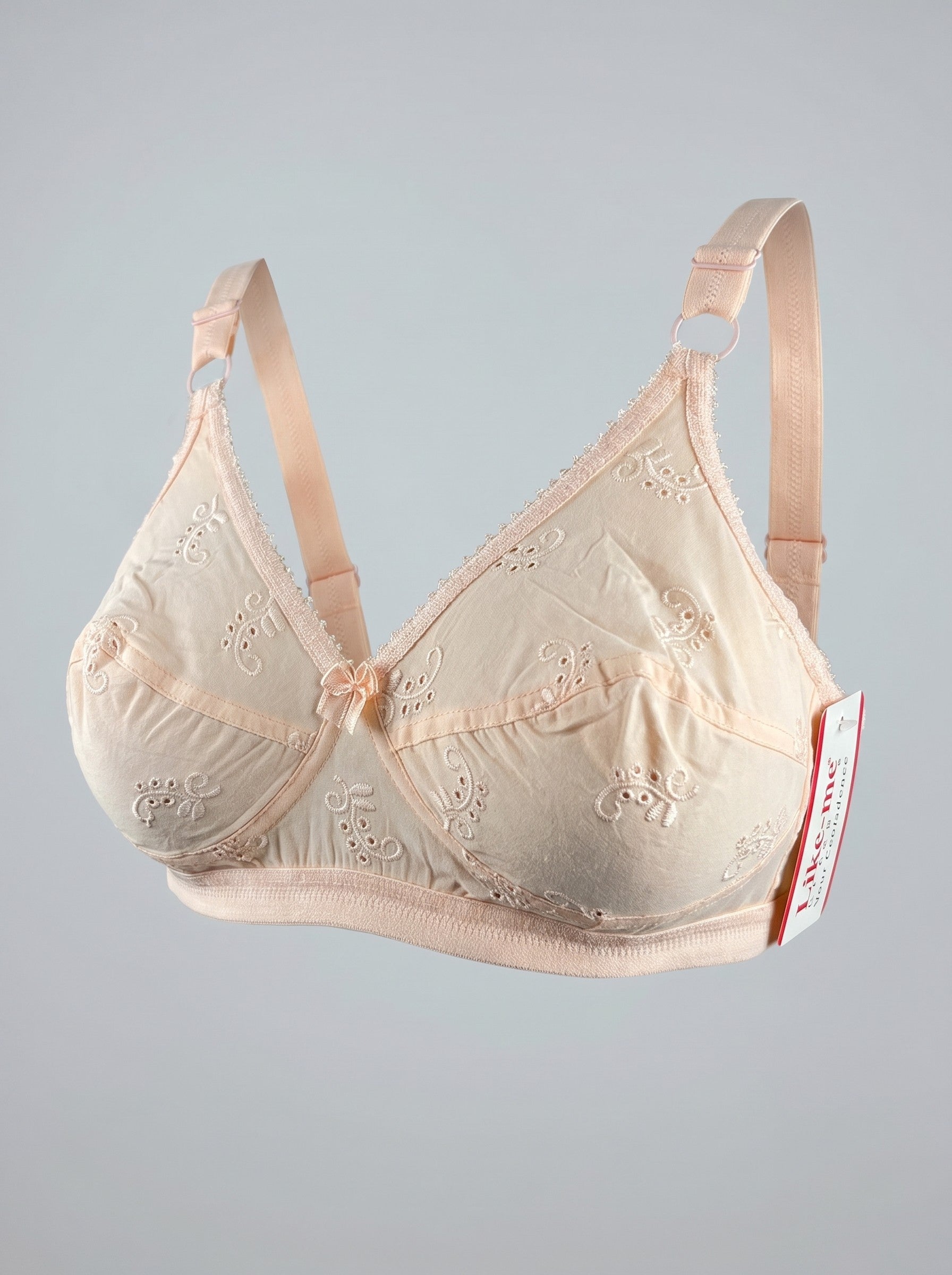 A light beige underwire bra with embroidered floral details and adjustable shoulder straps, shown against a neutral gray background with a brand tag on the right side. #color_peach