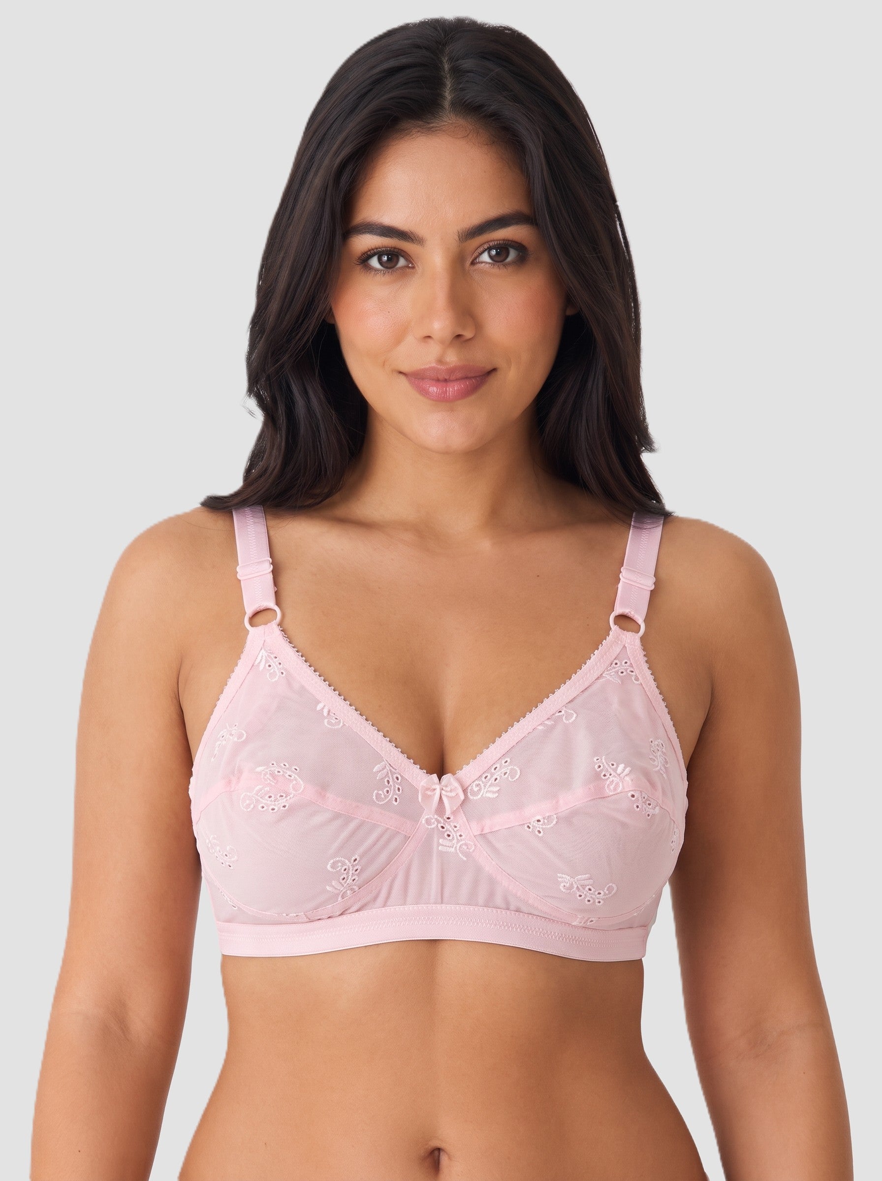 A woman modeling a light pink underwire bra with lace detailing and adjustable shoulder straps, set against a solid light gray background. #color_pink