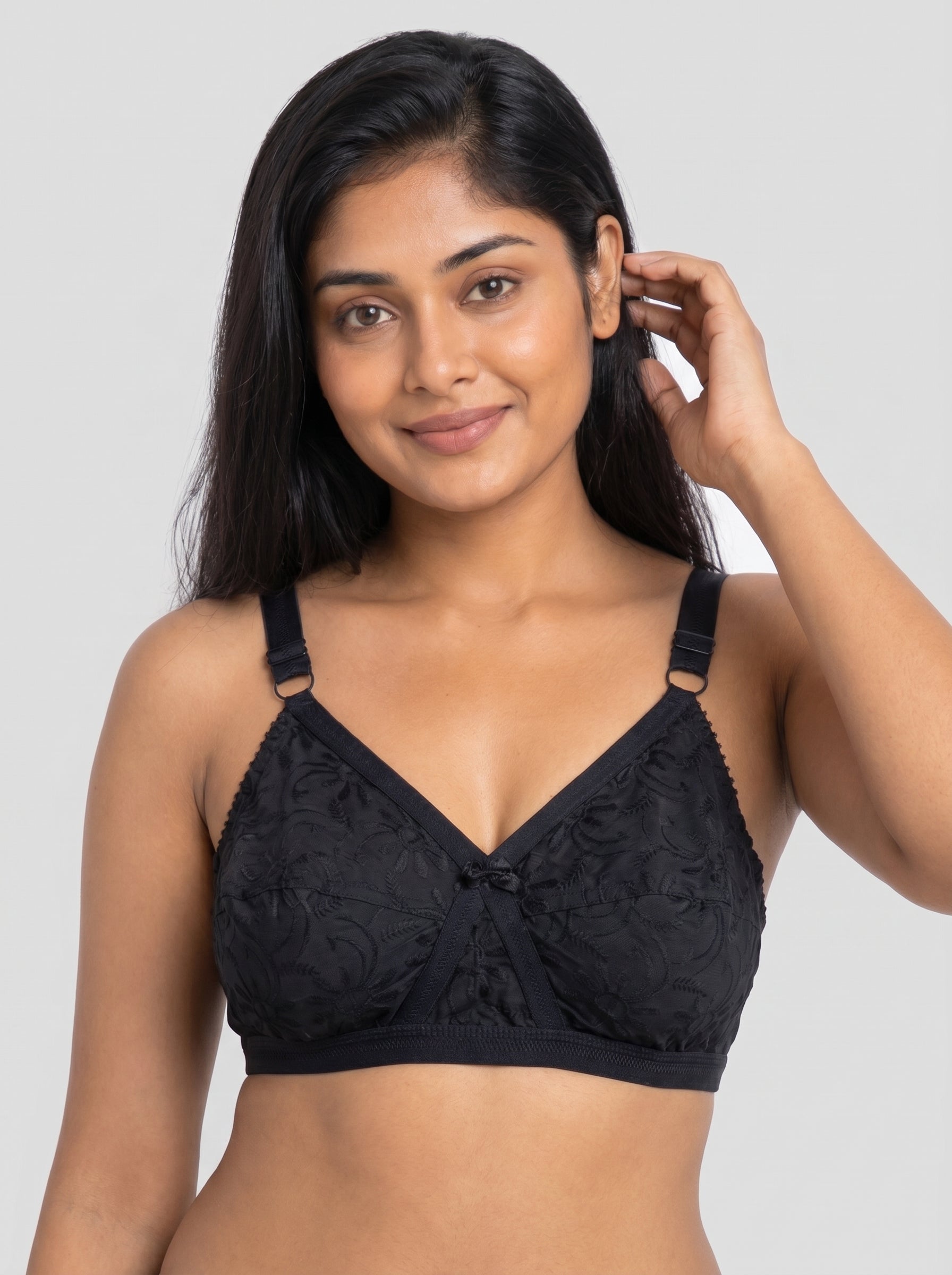 Woman wearing a black lace bralette against a plain background #color_black