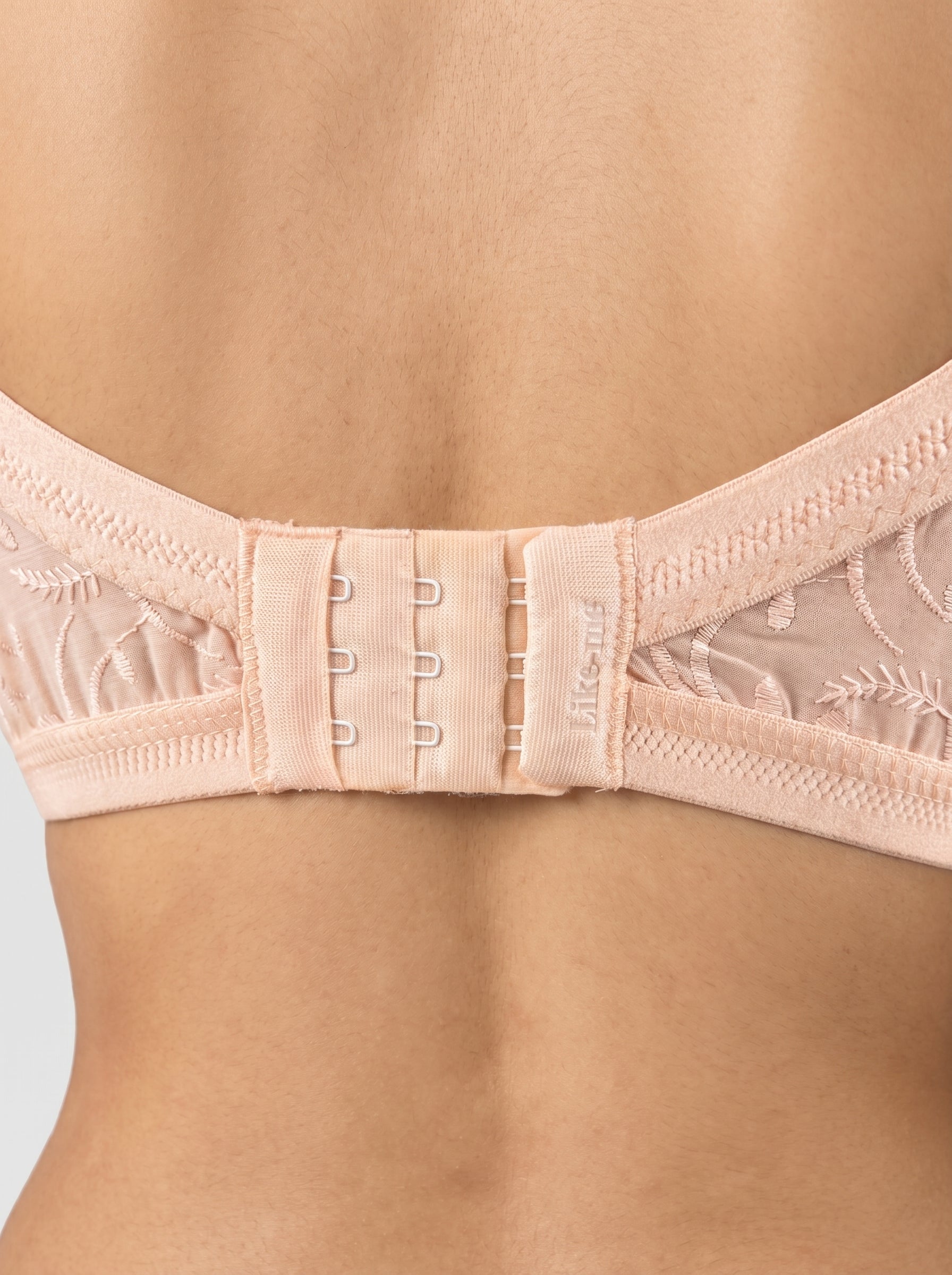 Close-up of a beige bra with lace details on a neutral background #color_peach