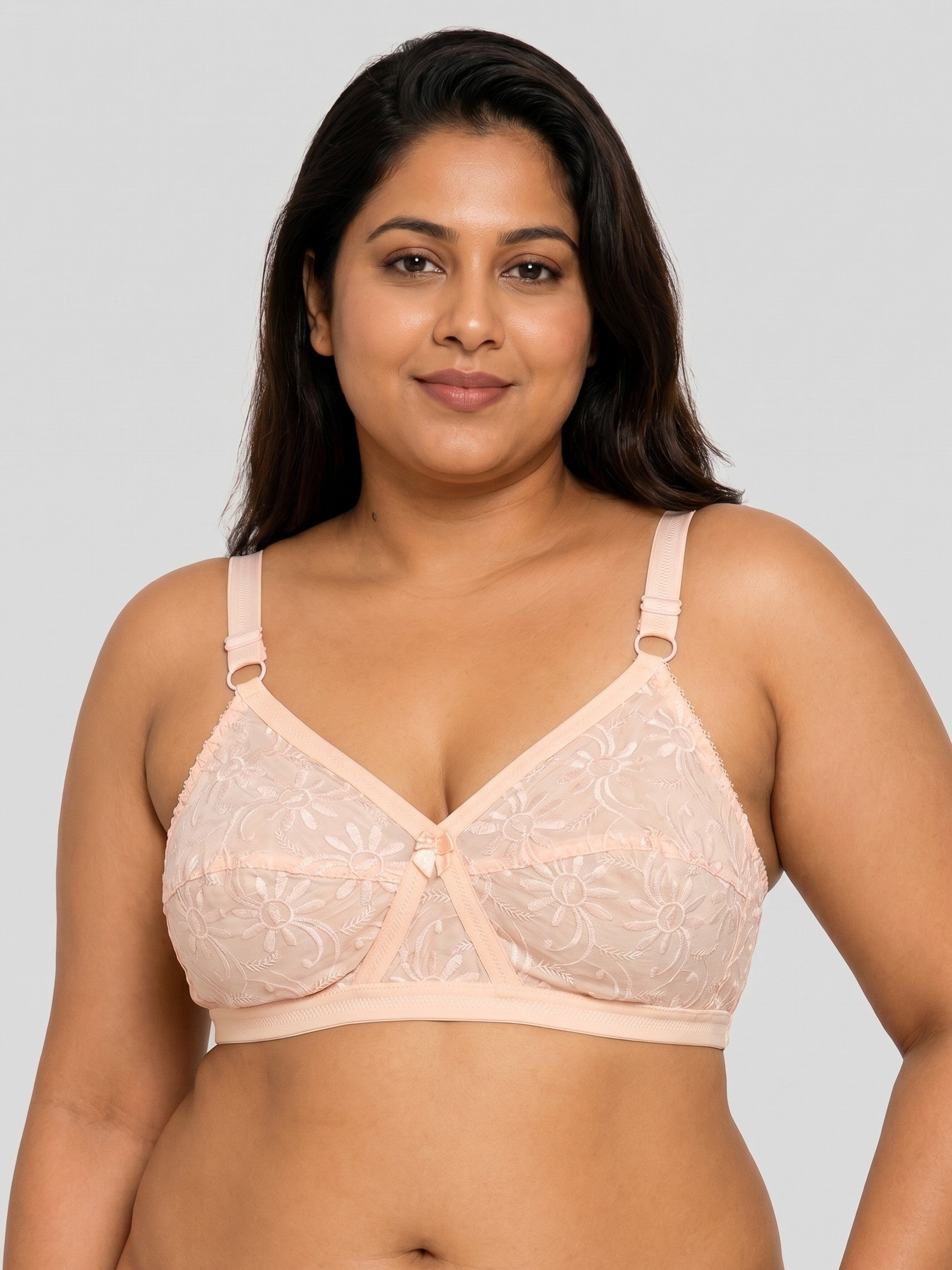 Woman wearing a beige lace bra against a plain background #color_peach