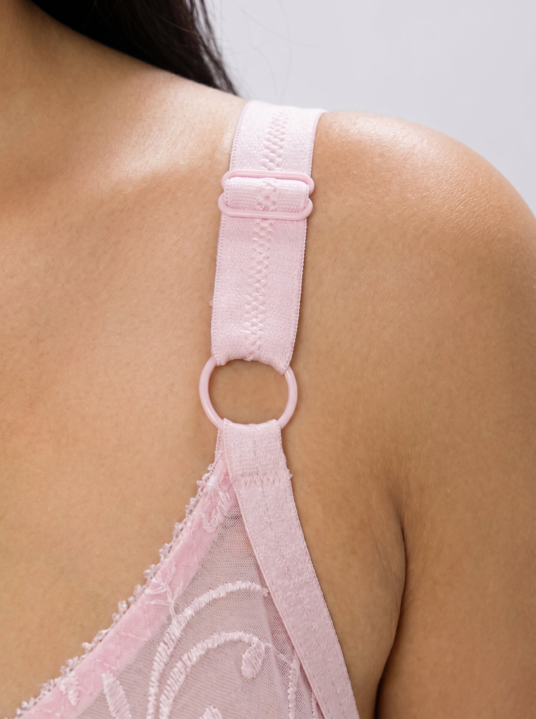 Close-up of a pink bra strap on a person's shoulder against a neutral background #color_pink