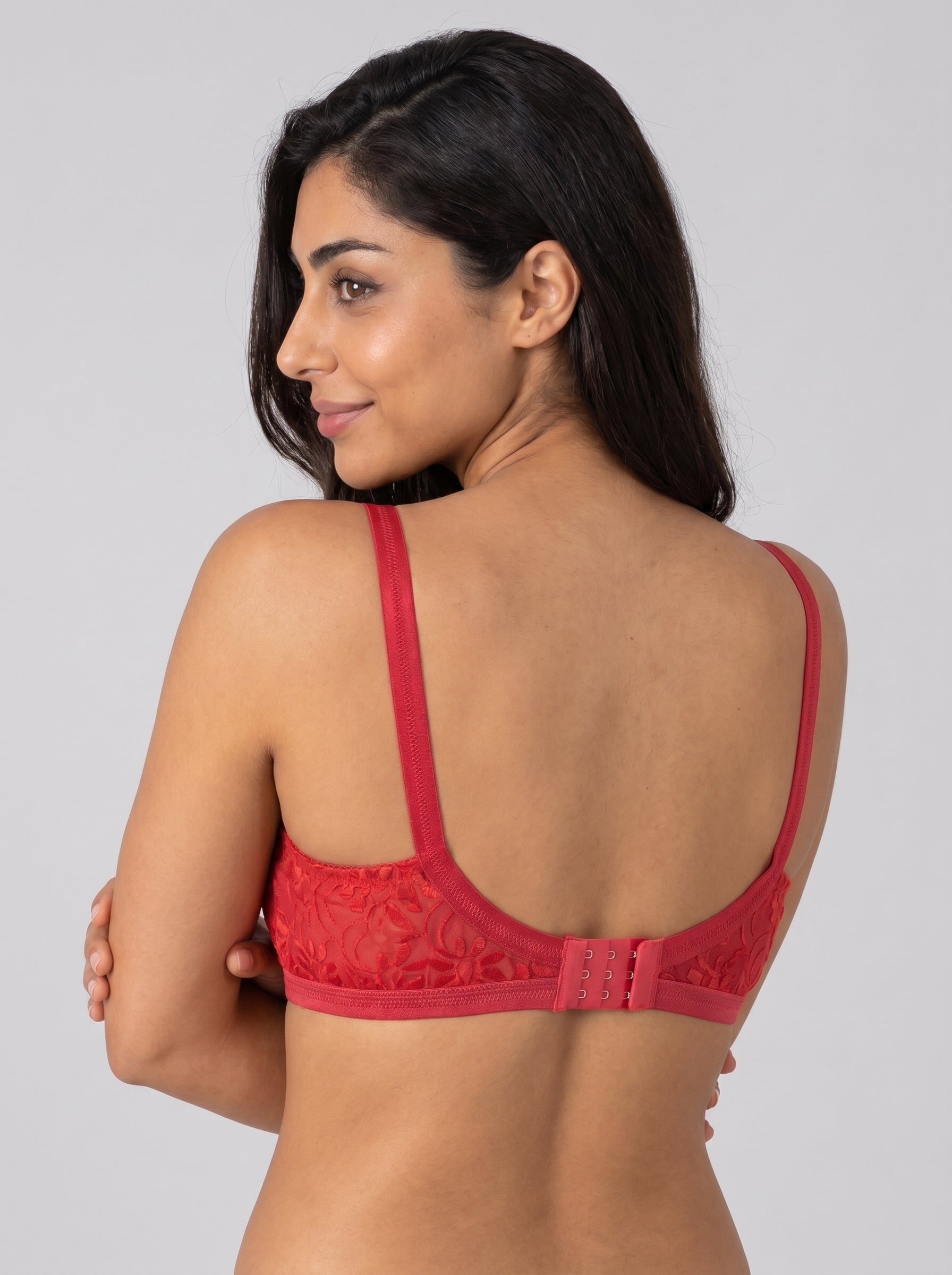 Woman wearing a red lace bralette against a gray background #color_red