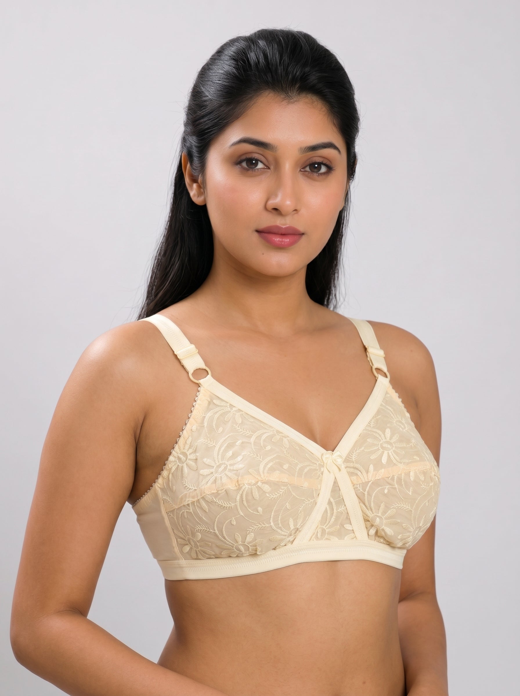 Woman wearing a beige lace bra against a plain background #color_skin