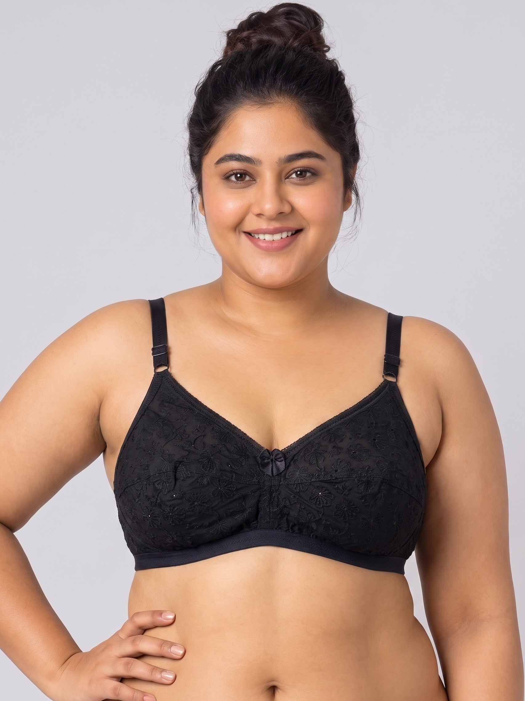 A plus-size woman wearing a black lace underwire bra with adjustable shoulder straps, photographed against a solid light gray studio background. #color_black