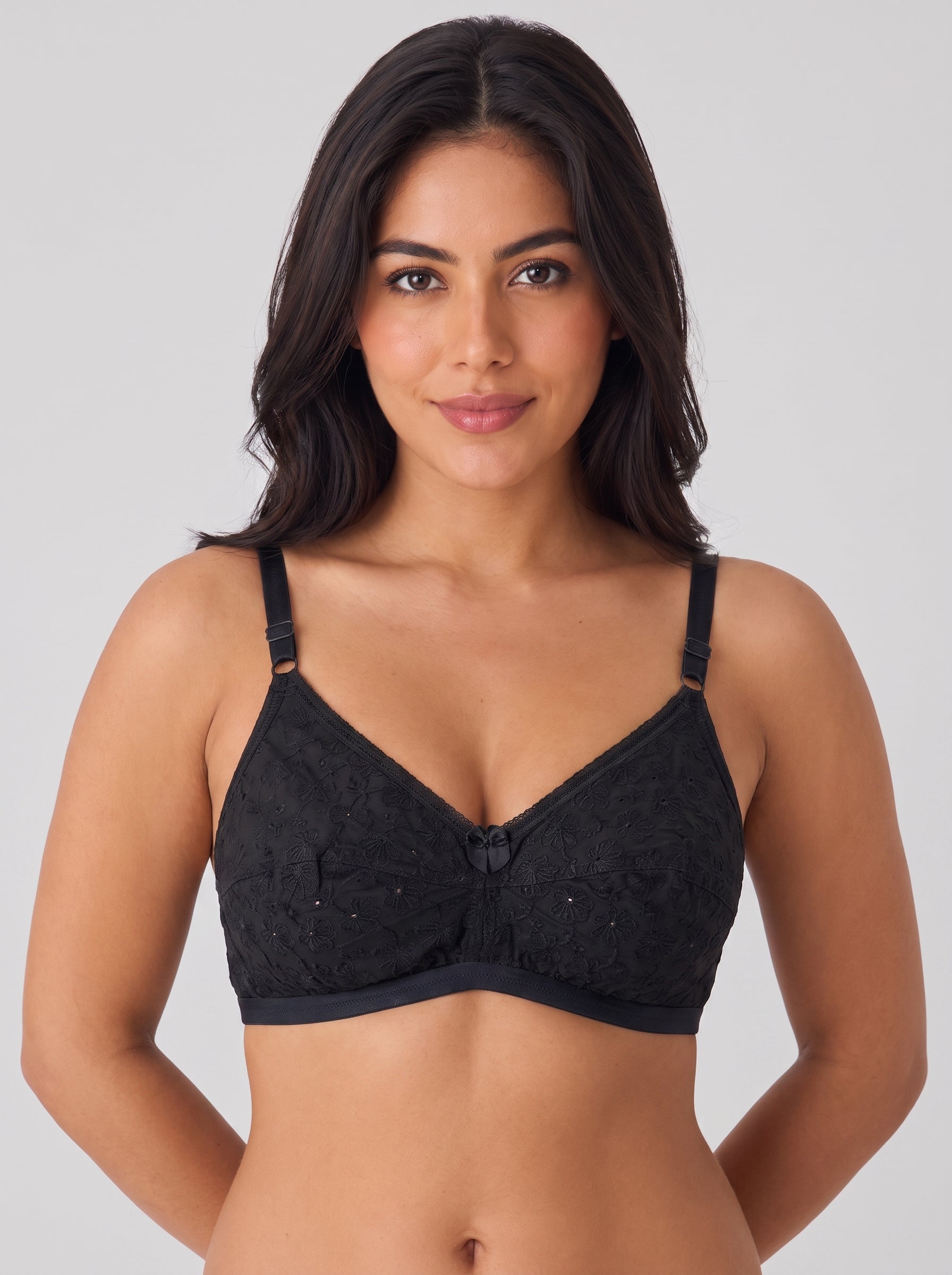 A woman modeling a black lace underwire bra with adjustable shoulder straps against a solid light gray background. #color_black