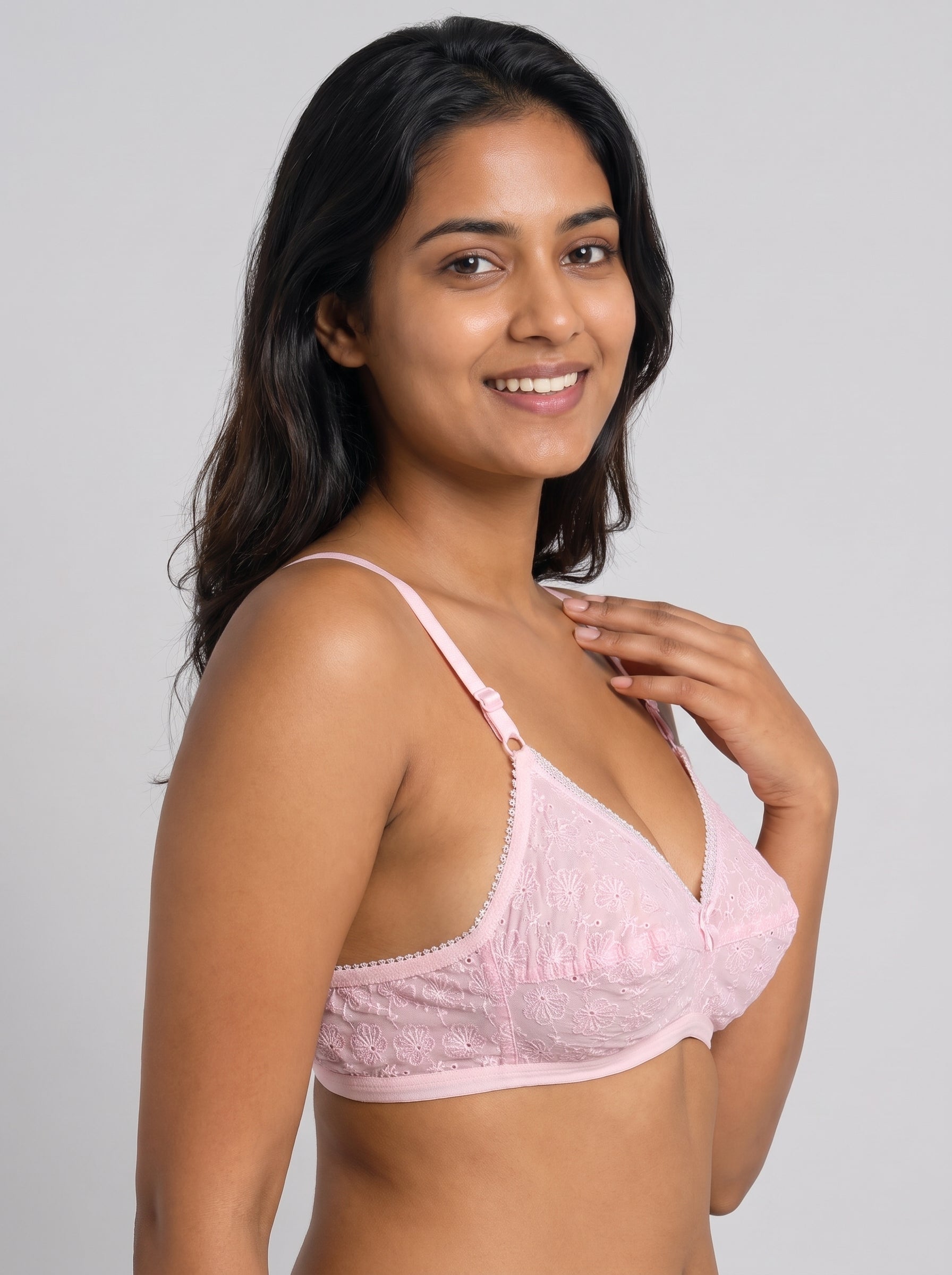A woman modeling a light pink lace underwire bra against a solid light gray background. #color_pink