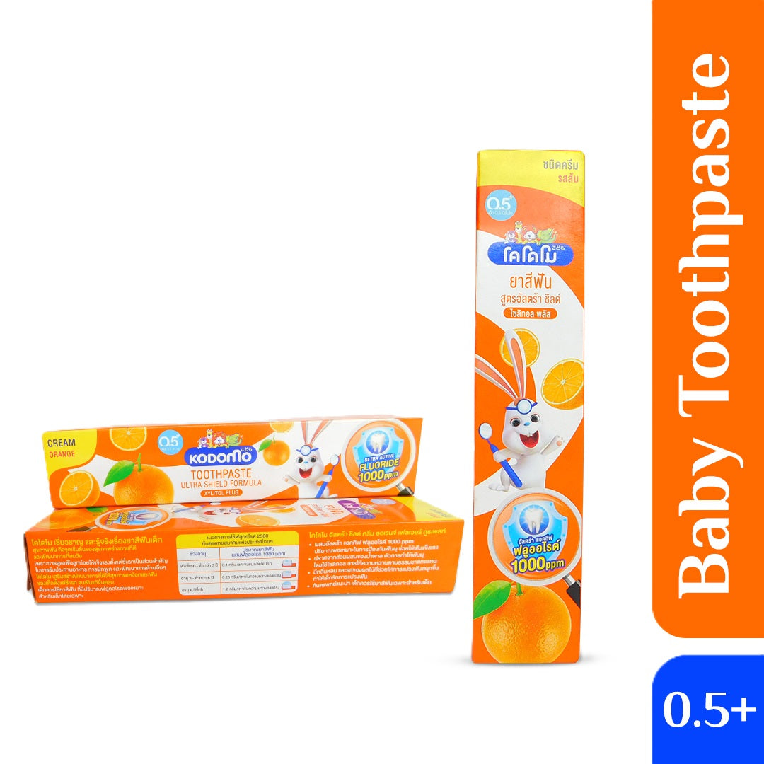 Kodomo Baby Toothpaste Ultra Shield Formula (Orange Cream) for 0.5+ years, showing front and side packaging with cartoon rabbit, orange slices, and fluoride label.