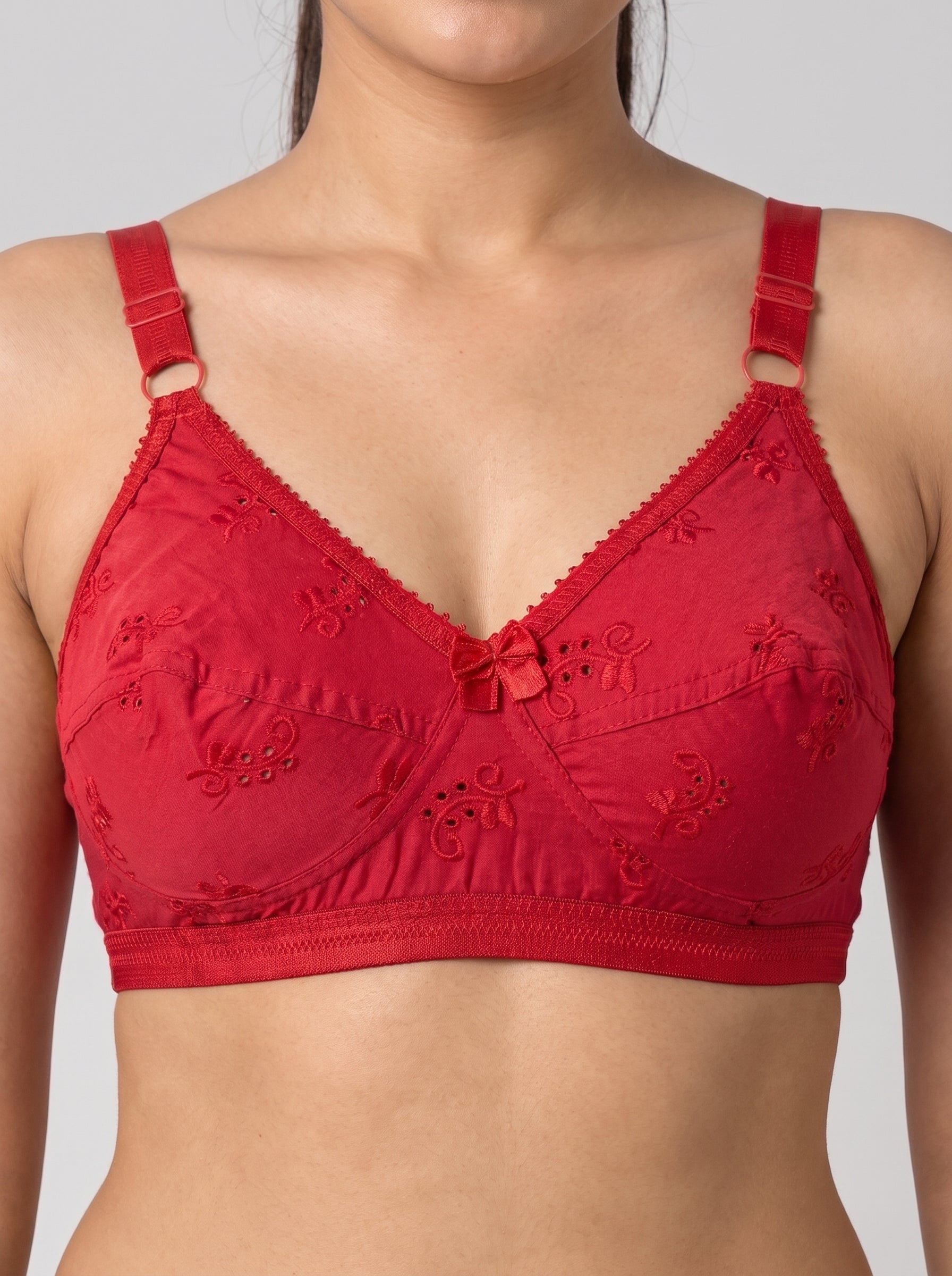 A red underwire bra with embroidered floral details and adjustable shoulder straps, shown on a model against a light gray background. #color_red