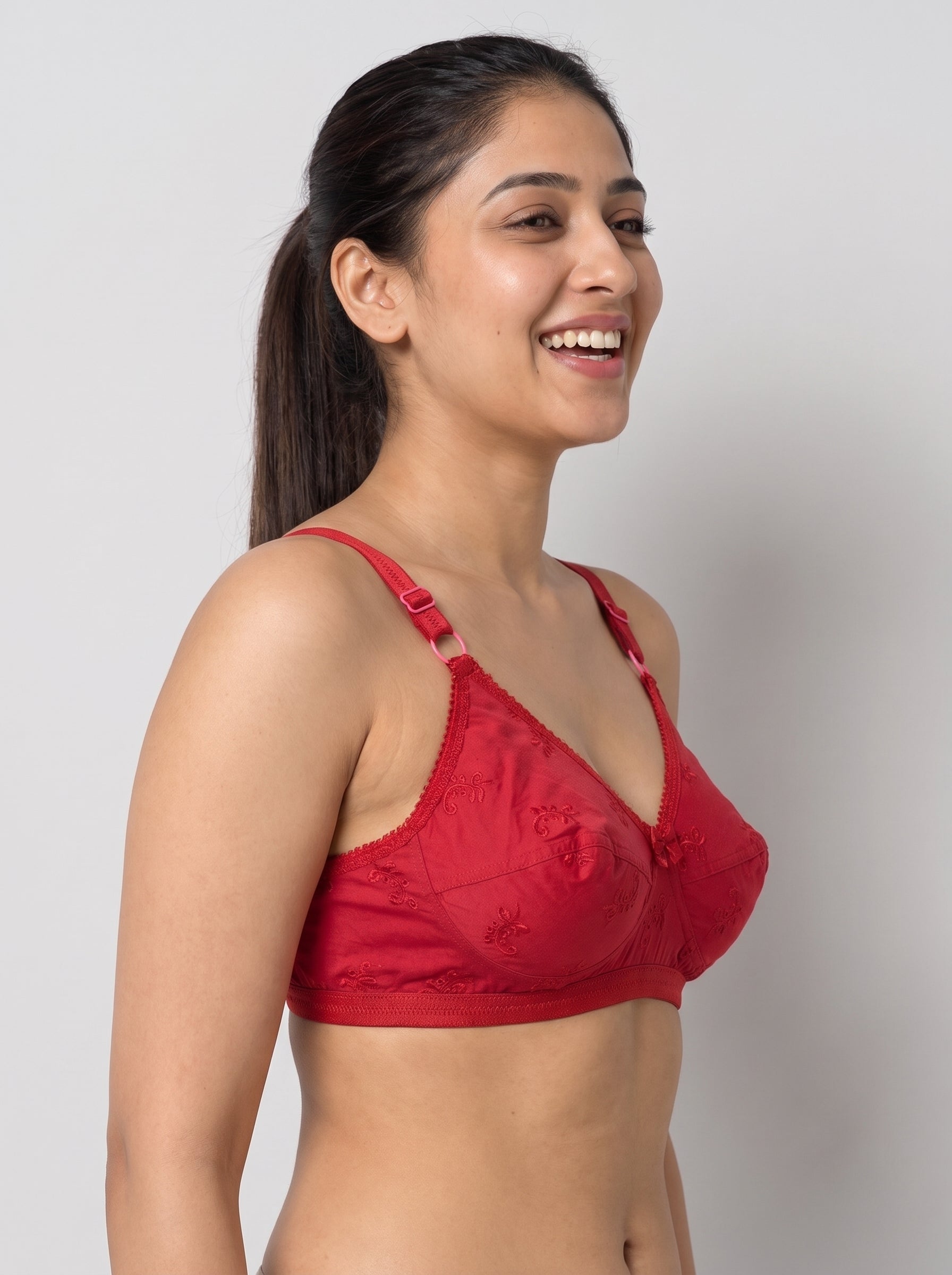 A woman wearing a red lace underwire bra, shown from the waist up against a plain light gray studio background. #color_red