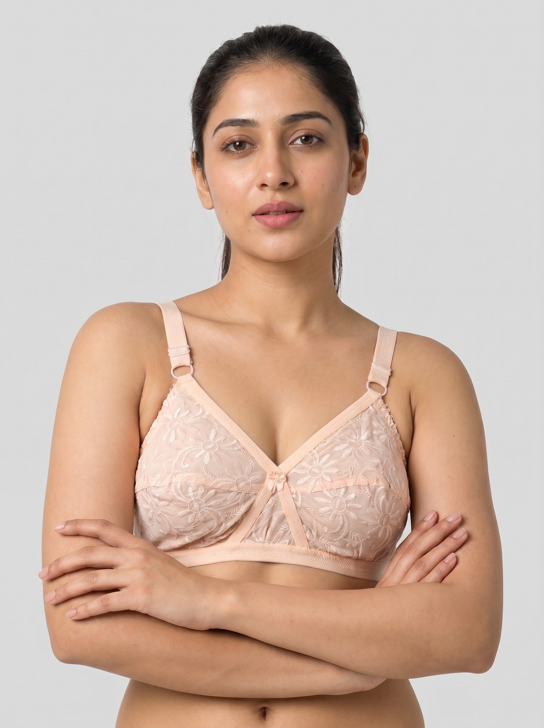 Woman wearing a beige lace bra against a plain background #color_peach