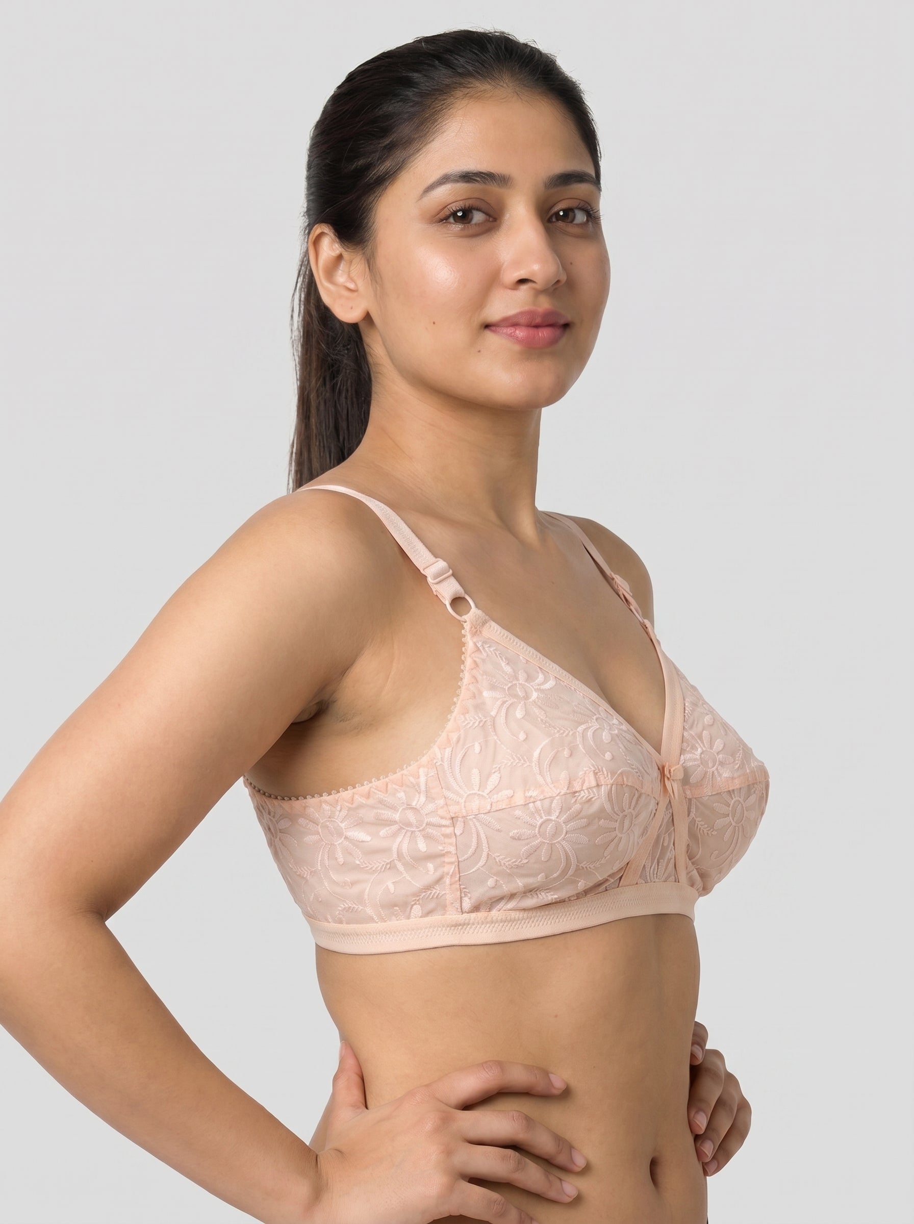 Woman wearing a light pink bralette against a plain background #color_peach