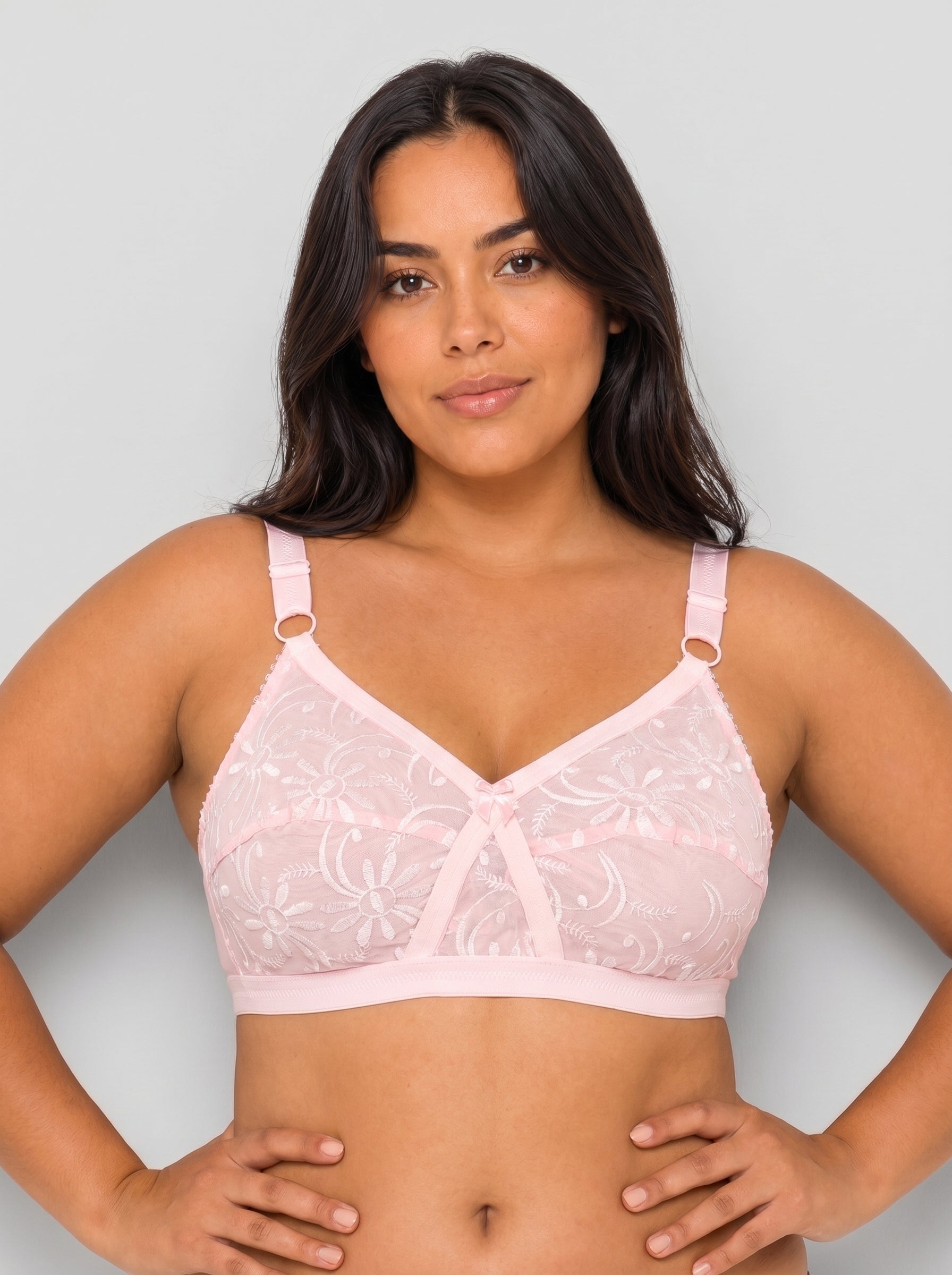 Woman wearing a pink lace bra against a plain background #color_pink