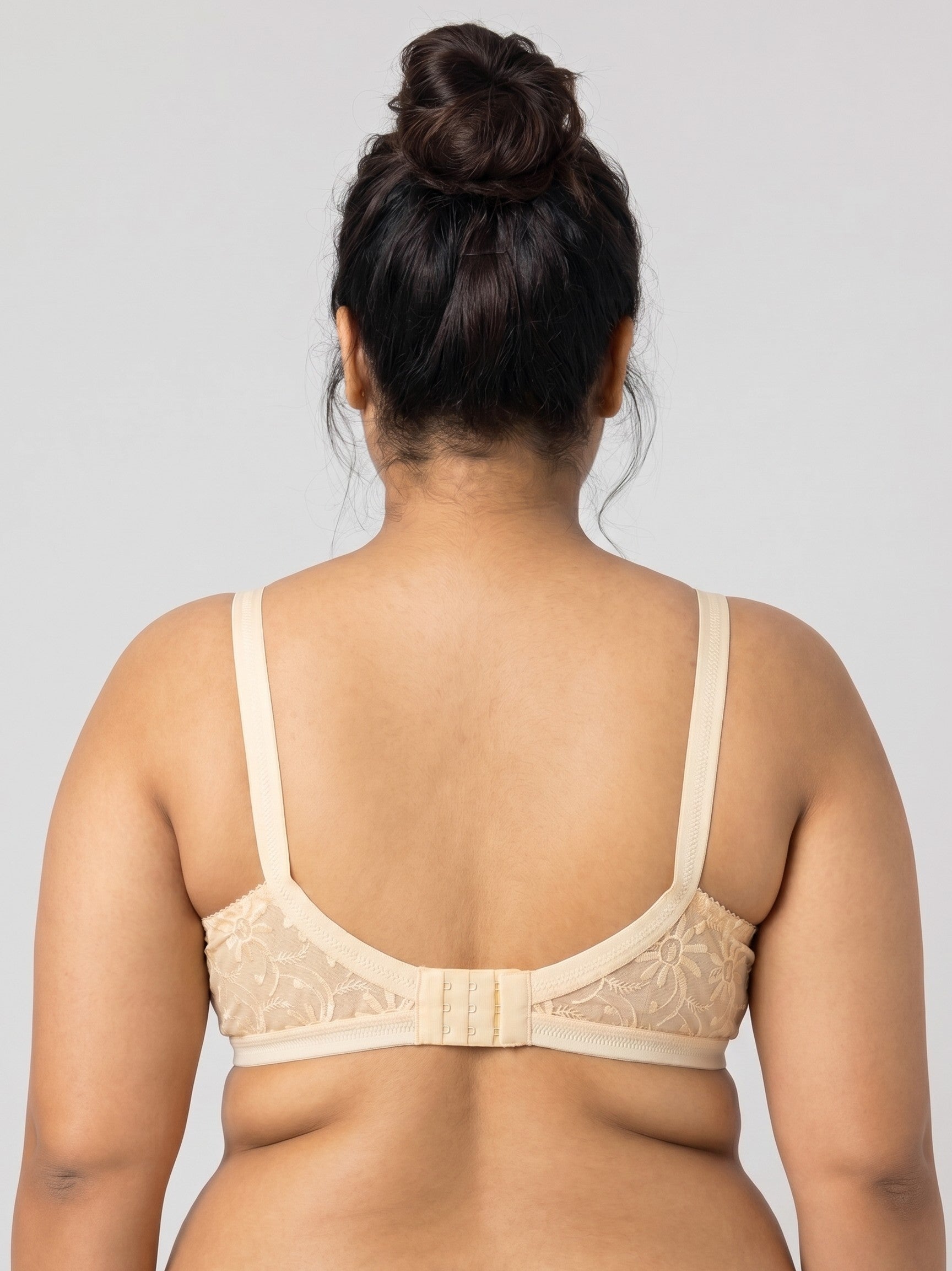 Woman wearing a beige bra against a plain background #color_skin