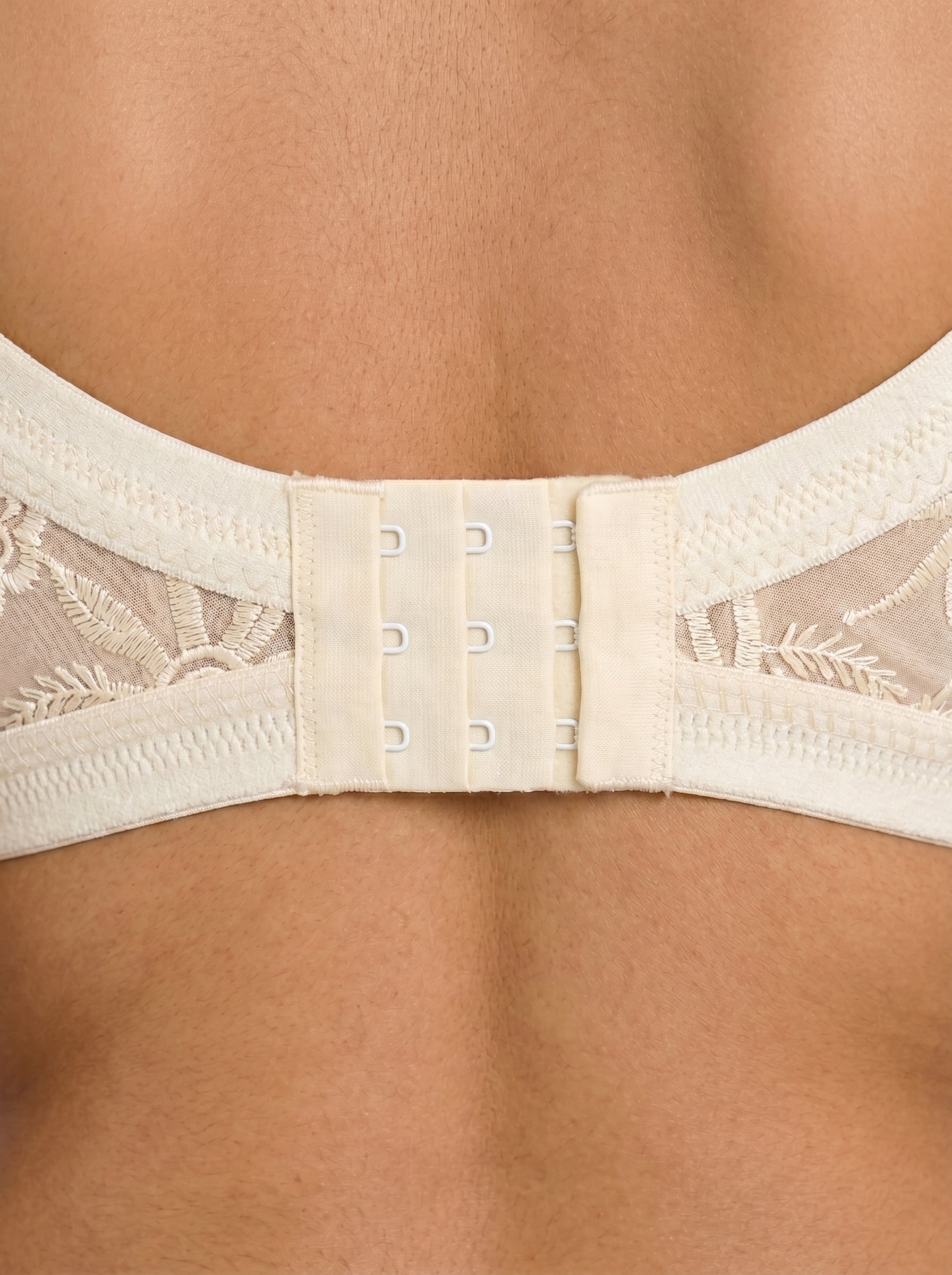 Beige bra with lace details on a person wearing it. #color_skin