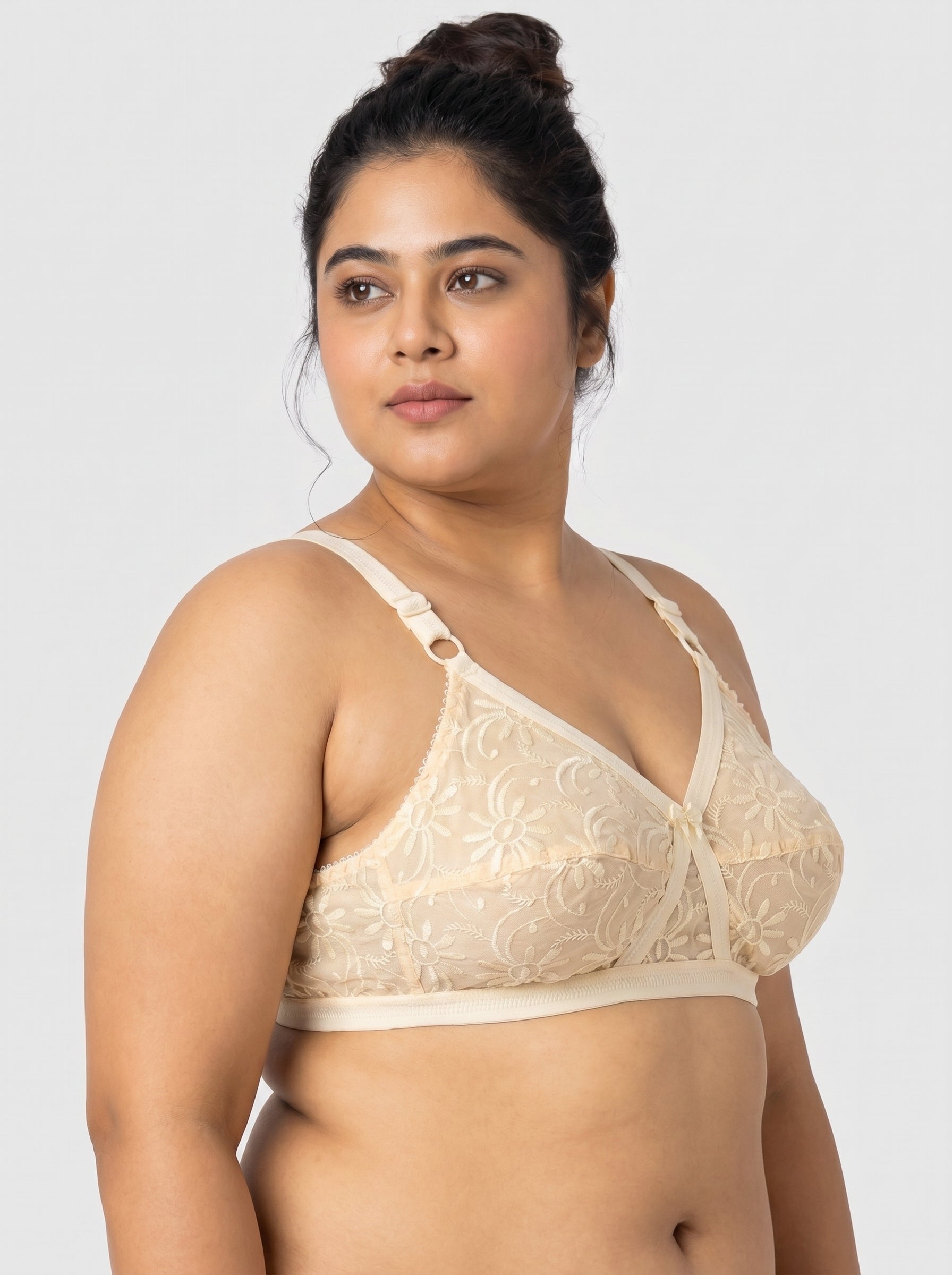 Woman wearing a beige bralette against a plain background #color_skin