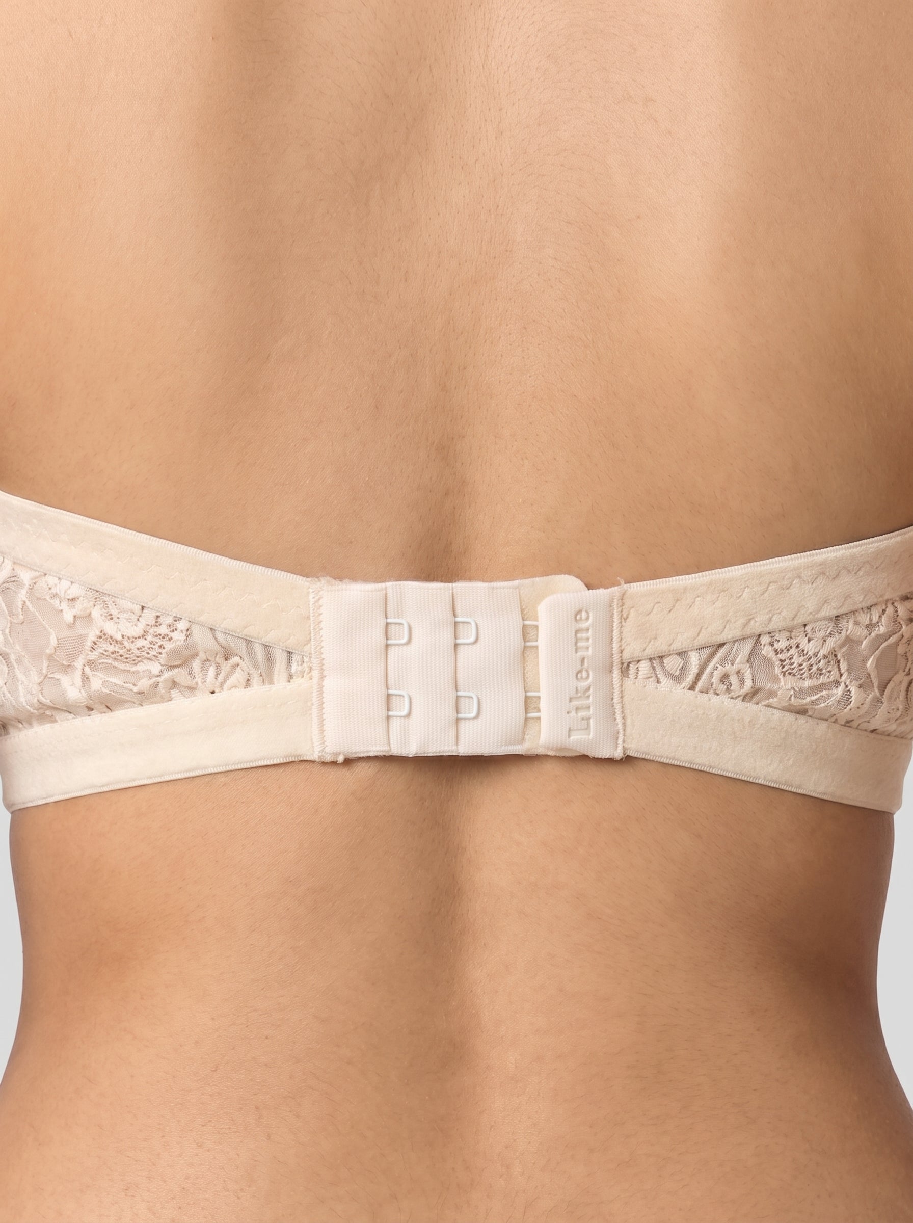Close-up of a beige underwire bra with floral lace cups and a triple-hook closure, shown on a model's back. #color_cream