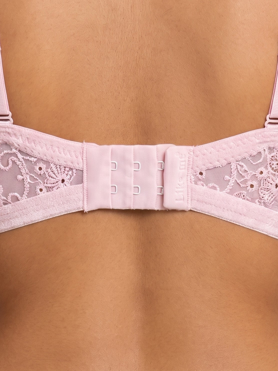 Close-up of the back strap and adjustable hook-and-eye closure of a light pink lace bra worn by a model. #color_pink