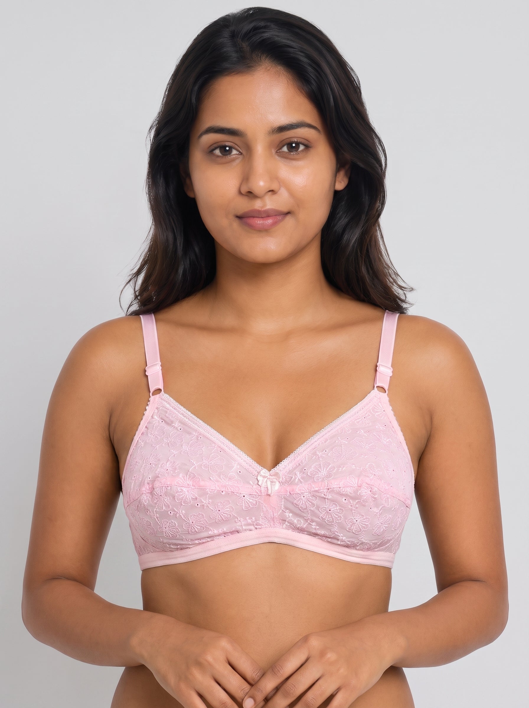 A woman modeling a light pink lace underwire bra against a solid light gray background. #color_pink