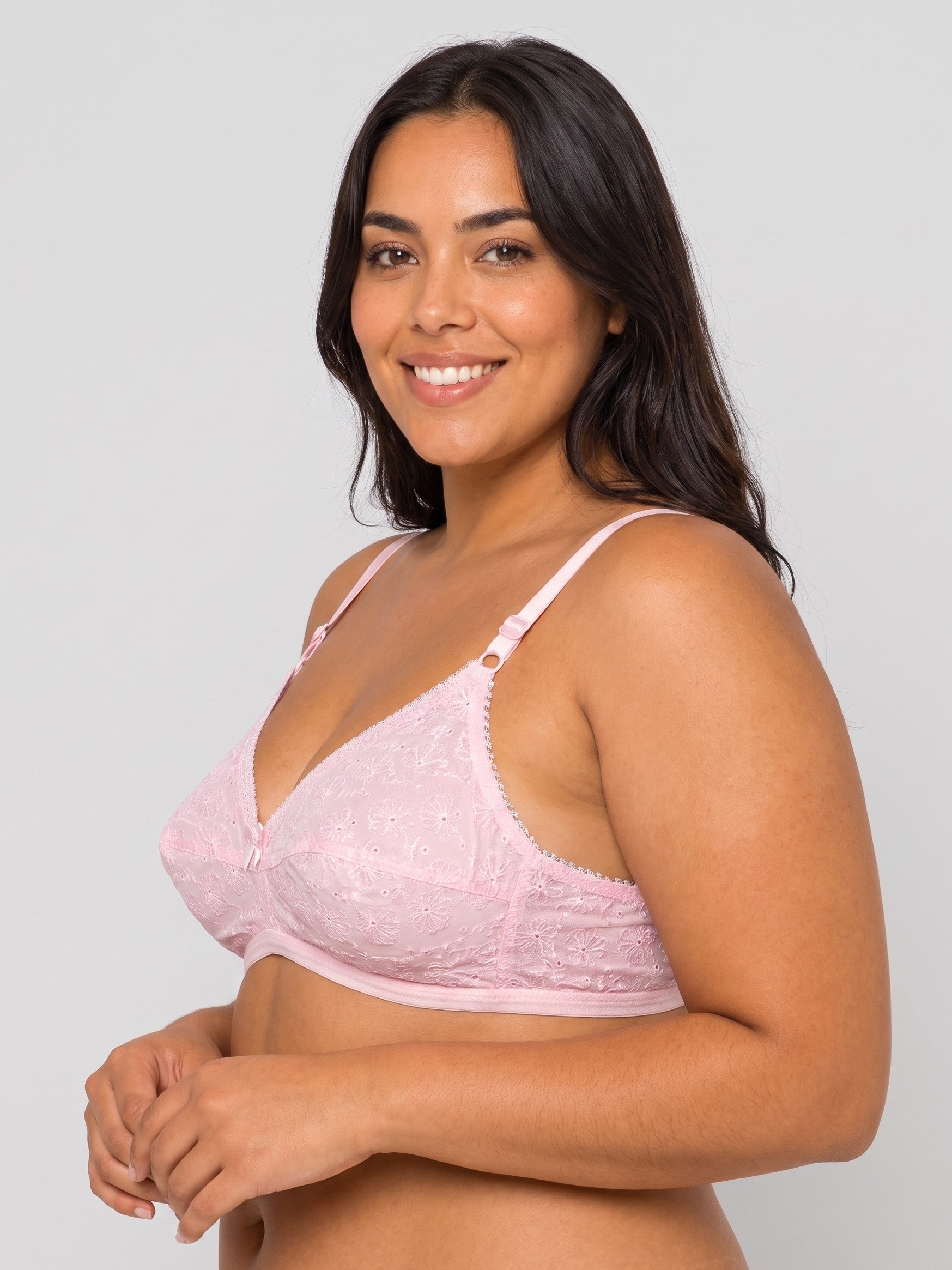 A woman modeling a light pink lace underwire bra against a solid light gray background. #color_pink